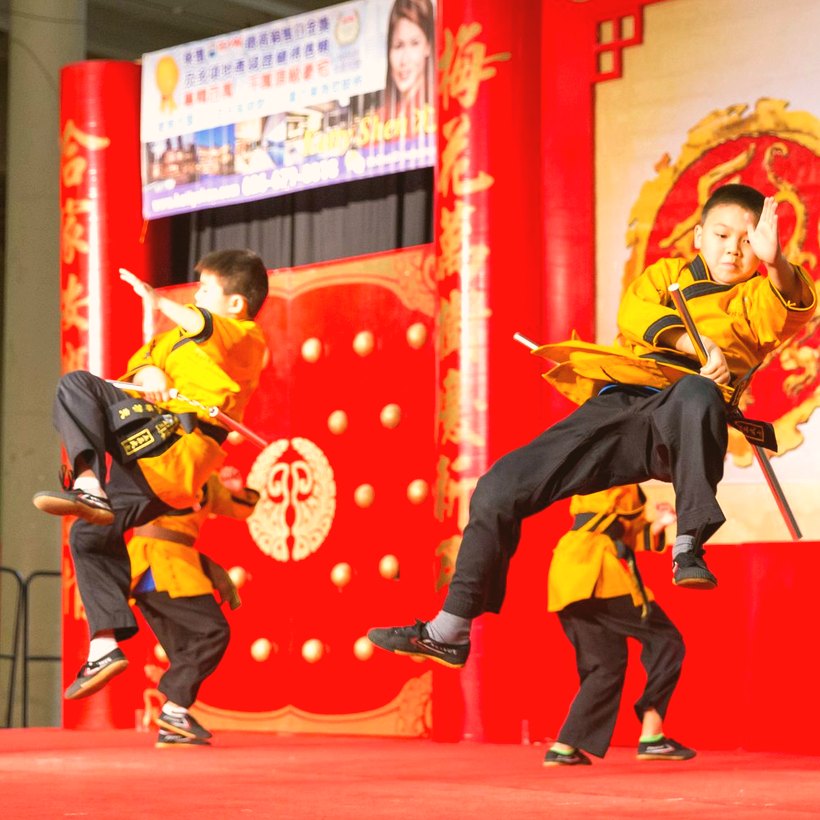 Young martial artists leaping mid-kick on stage