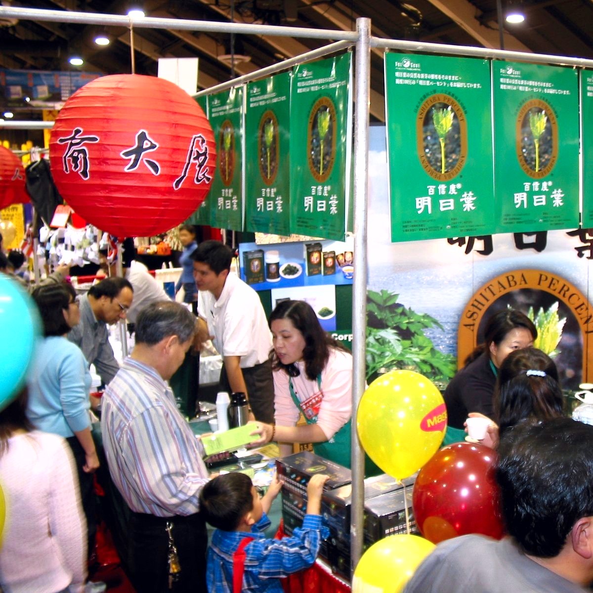 Vendor booth with a red paper lantern and attendees browsing products