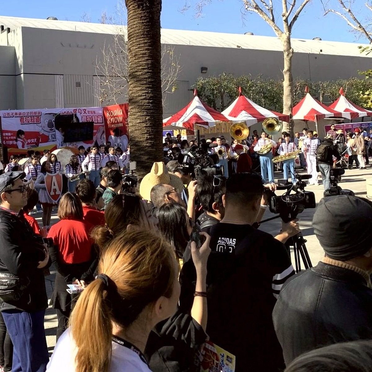 Row of red and white outdoor vendor tents with a marching band performing nearby