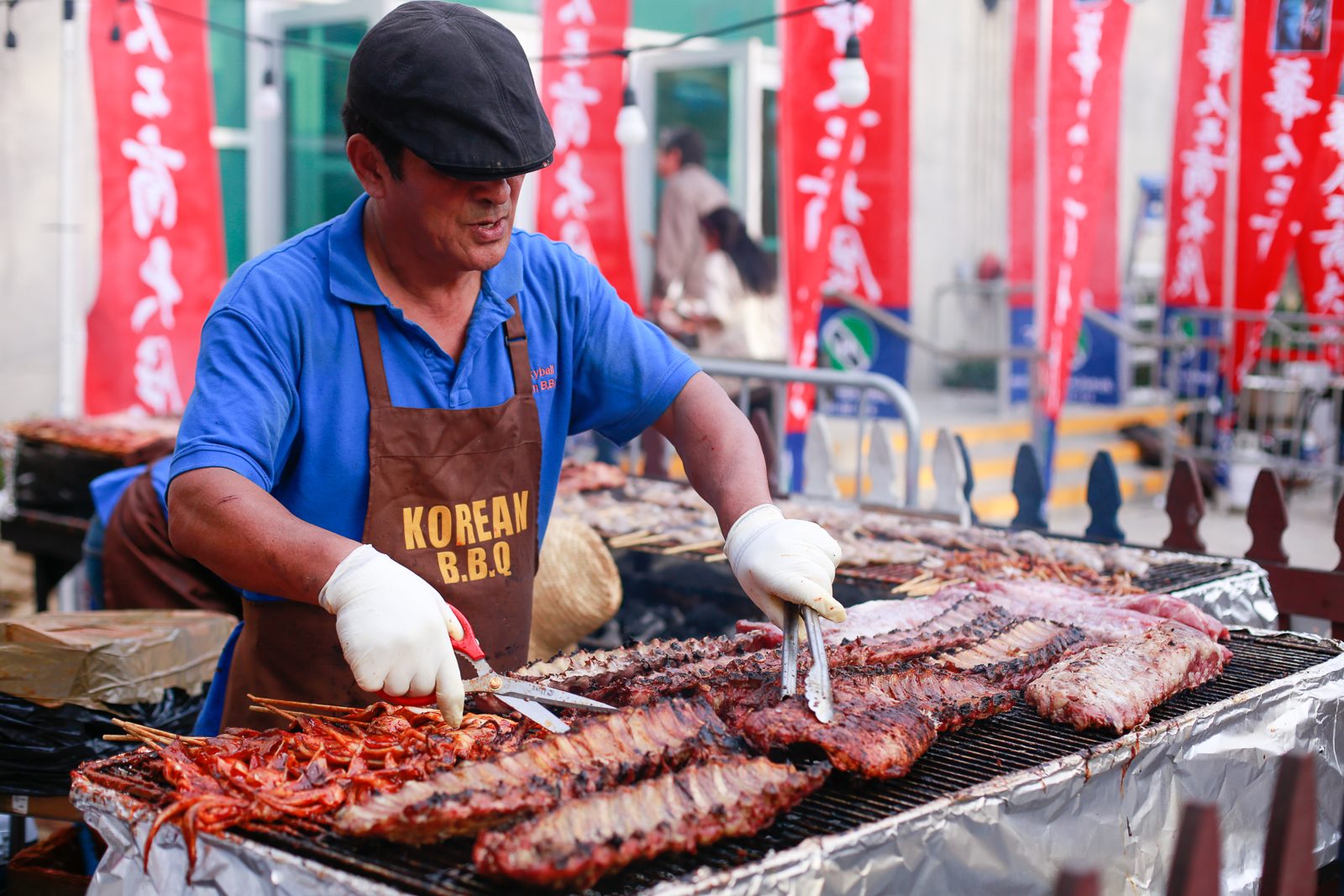 Korean BBQ vendor grilling ribs and skewers at an outdoor booth